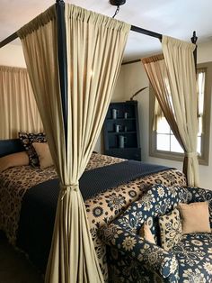 a canopy bed sitting in the middle of a bedroom next to a blue couch and chair