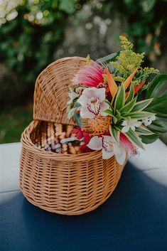 a basket filled with flowers sitting on top of a table next to a blue table cloth