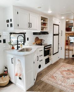 a kitchen with white cabinets and an area rug on the floor in front of it