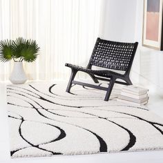 a black and white rug with a chair in the middle next to a potted plant