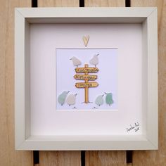 a white frame holds a wooden sign with birds on it and the words happy friday