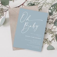 a blue and white baby shower with greenery on the side, next to it is a card that says oh baby