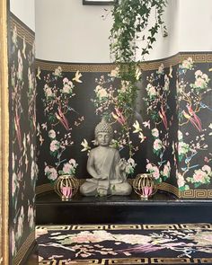 a buddha statue sitting on top of a wooden bench next to a wall covered in flowers