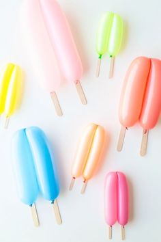 four popsicles are lined up in different colors on a white surface with wooden sticks sticking out of them