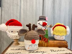 three crocheted christmas hats sitting on top of a wooden table next to each other