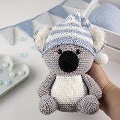 a crocheted koala bear with a hat on it's head sitting in front of a bed