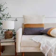 a living room with a couch, lamp and pillows on it's side table