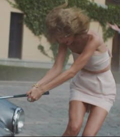 a woman in a short dress cleaning a car