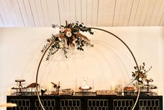 an arch decorated with flowers and greenery stands in front of a black buffet table