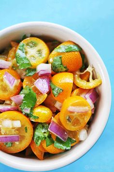 a white bowl filled with sliced up oranges and onions on top of a blue surface