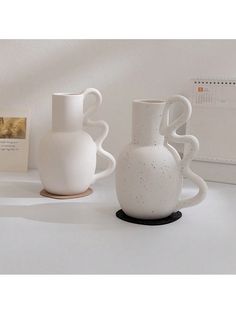 three white vases sitting on top of a table