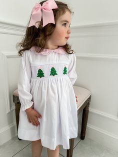 PRE-ORDER - SHIPPING IN NOVEMBER. ESTIMATE DELIVERY DATE PLEASE READ: If you are ordering in stock items along with PRE-ORDER items, they will ship on the PRE-ORDER listing date. If you need the in stock item earlier, please place a separate order.  The perfect little white holiday dress embellished with embroidered Christmas trees and a scalloped sweet pink collar! Clothing Care Instructions: Machine wash gentle. Do not bleach. Tumble dry delicate at low heat. Iron at medium. If the item that y Smocked Christmas Outfits, Winter Christmas Outfits, White Holiday Dress, Smocked Christmas Dresses, Embroidered Christmas, Christmas Outfits, Pink Collar, Pink Collars, Gender Neutral Baby Clothes