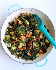 a pan filled with broccoli, chickpeas and carrots next to a blue spatula