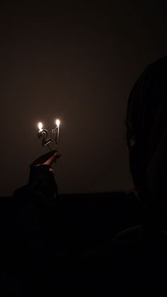 the person is holding two small candles in their hand, with one light on top