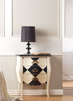 a black and white dresser sitting next to a lamp