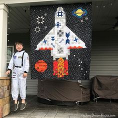 a young boy standing next to a space shuttle quilt