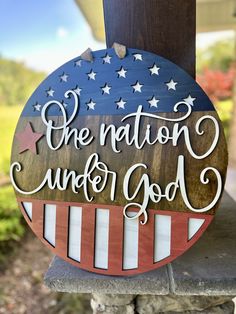 a wooden sign with the words one nation under god on it and an american flag