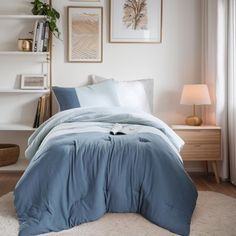 a bed with blue comforter and pillows in a bedroom next to a book shelf