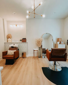 A caramel-colored shampoo system and styling chair are sitting away from each other while facing the opposite direction. In front of the styling chair are an arched mirror and wooden styling station with gold hardware. My Salon Suite, Manicure Tables, Nail Salon Equipment, Minerva Beauty, Beauty Room Salon