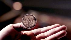 a person holding up a small piece of metal with a triangle in it's center