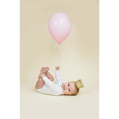 a baby laying on its back holding a balloon