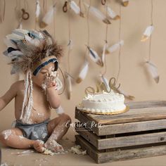 a baby sitting in front of a cake with feathers on it