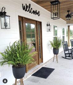 a porch with chairs and potted plants on the front steps, along with welcome sign