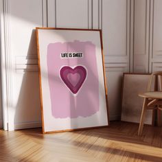 a pink poster with a heart on it next to a wooden chair and white wall