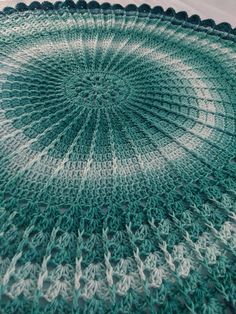 a green and white crocheted doily is on the floor with it's center