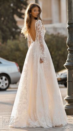 a woman in a wedding dress standing next to a street light with her back turned