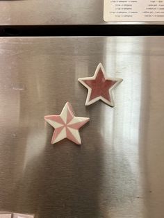 two star shaped cookies sitting on top of a metal refrigerator freezer next to each other