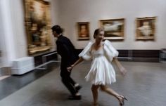 a man and woman are walking in an art gallery