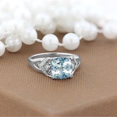 a blue and white stone ring sitting on top of a table next to some pearls