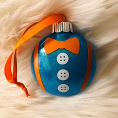 a blue ornament with an orange bow tie and two buttons on the front