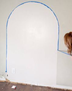 a woman painting a wall with blue tape