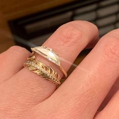 a woman's hand with two gold rings on it and a white diamond in the middle