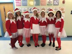 a group of women dressed up in christmas costumes posing for a photo with santa hats and tutu skirts