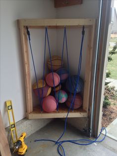 a shelf filled with lots of different colored balls in it's storage area next to a window