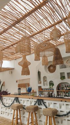 an indoor bar with wicker stools and hanging lights