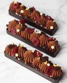 three pieces of chocolate dessert sitting on top of a white marble countertop next to each other