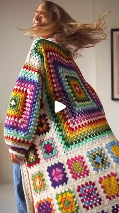 a woman is holding a colorful crocheted blanket