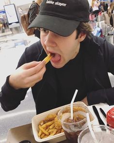 a man is eating french fries and drinking soda at a table with other food items