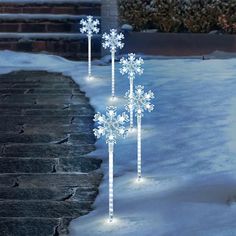 three snowflakes are standing in the snow next to some steps and bushes