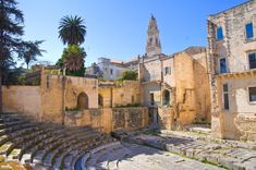 an old theatre with stone steps and palm trees in the background