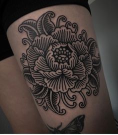 a woman's thigh with a black and white flower tattoo on it