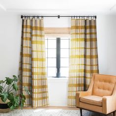 an orange chair sitting in front of a window next to a potted green plant