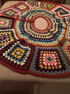 a multicolored crocheted rug on top of a bed in a room