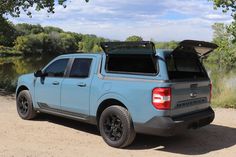 a blue pick up truck parked next to a river