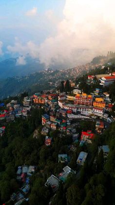 an aerial view of a city with mountains in the background and clouds hovering over it