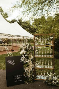 an outdoor event with white flowers and wine glasses on display in front of a tent